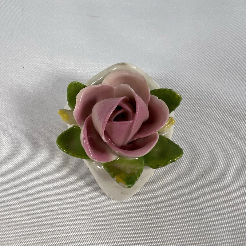 Pink porcelain rose figurine with green leaf accents, flower crown base