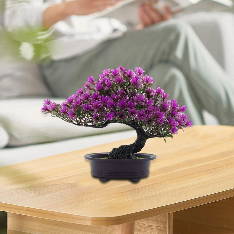 Small artificial bonsai tree with purple blossoms in a dark pot