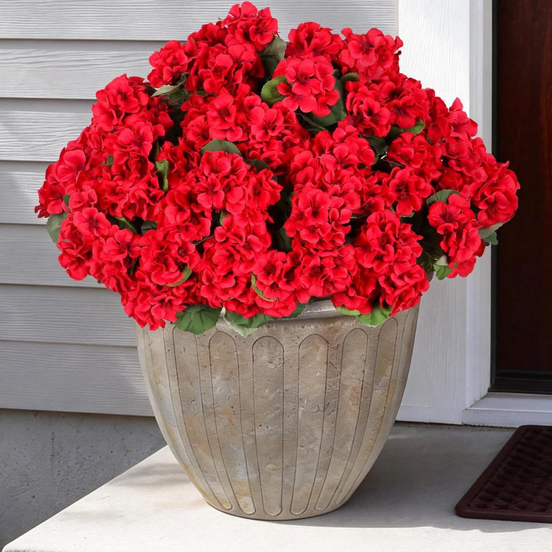 Artificial red geranium-style flowers with green leaves in a gray ribbed planter pot