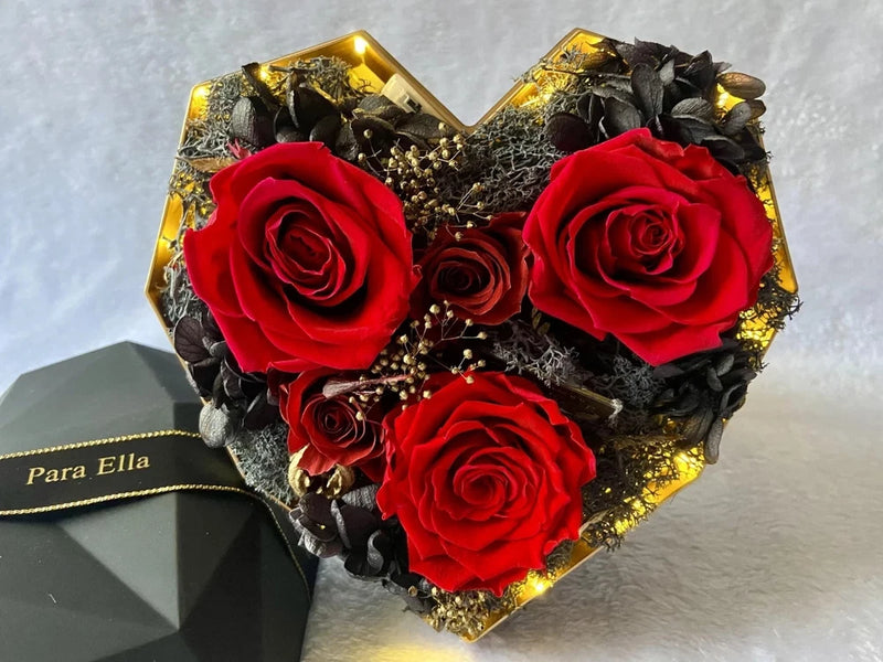 Heart-shaped flower gift box with red roses, gold accents, and ribbon