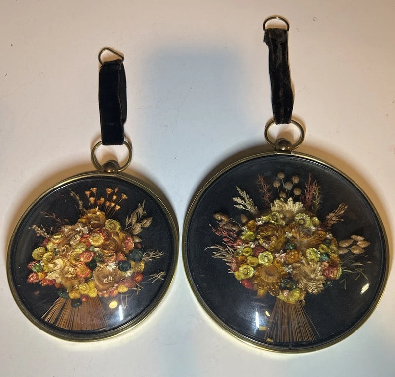 Set of 2 round domed-glass wall hangings with gold frames and dried floral bouquets
