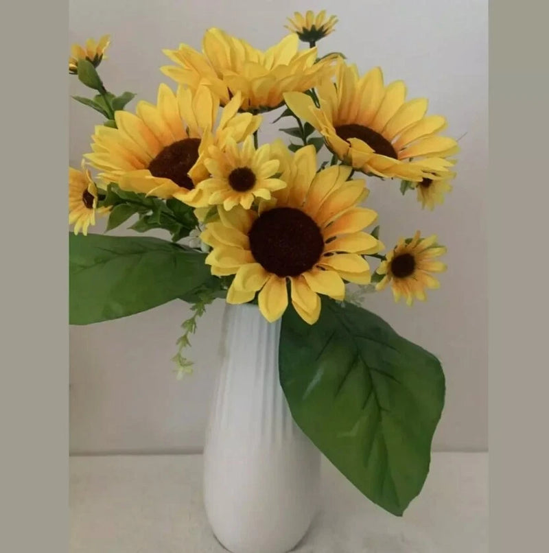 Artificial silk sunflower bouquet with yellow flowers, dark centers, and green leaves in white vase