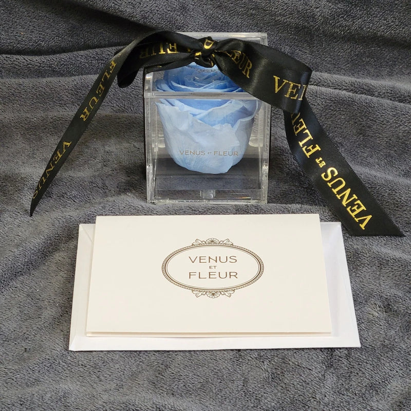 Acrylic storage box with blue eternity rose and white note card with Venus et Fleur logo