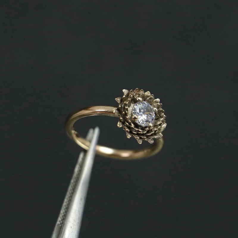 Gold-tone ring with sunflower flower-shaped prong setting and round moissanite center stone
