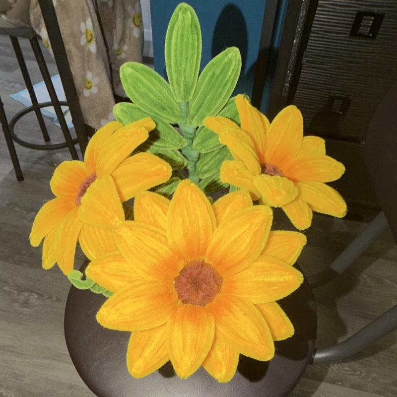 Yellow artificial sunflower arrangement with green leaves in a basket