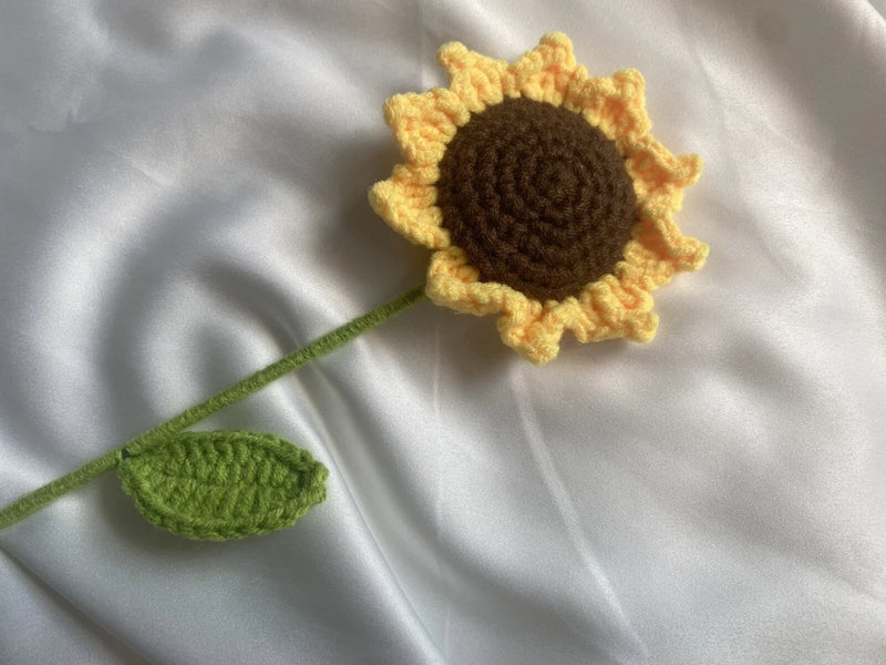 Handmade crochet sunflower with yellow petals, brown center, green stem and leaf