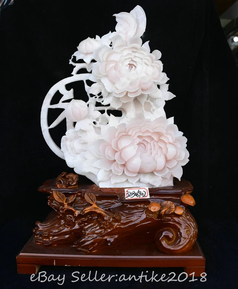 Carved peony and butterfly statue with white and pale pink flowers on dark wooden base