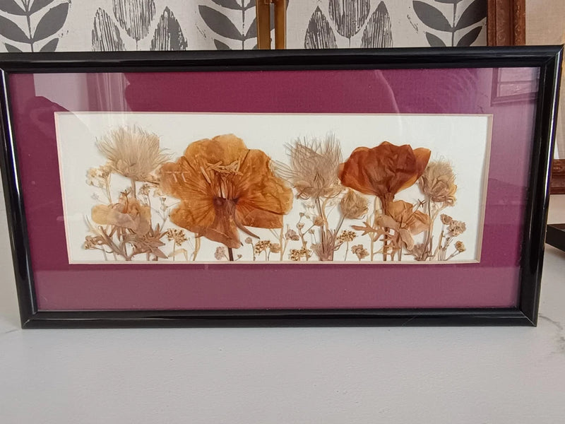 Framed pressed dried wildflower wall art with orange, tan, and white blooms