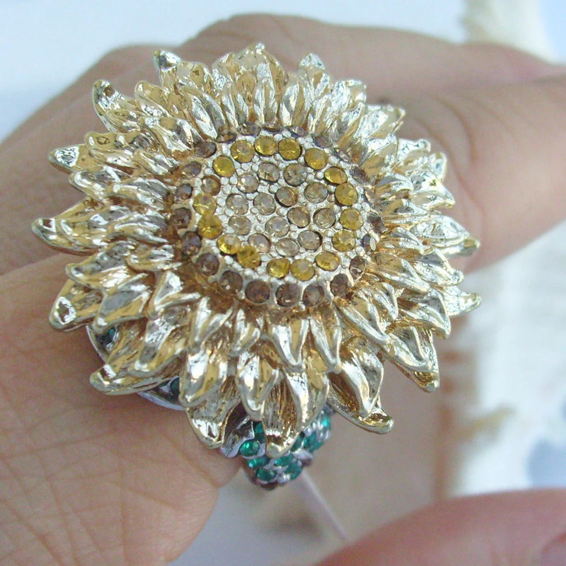 Gold-tone sunflower ring with yellow center rhinestone and small green stones