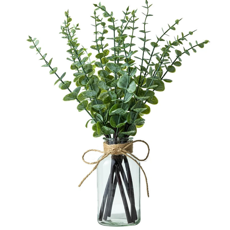 Artificial eucalyptus stems in clear glass vase with twine wrap, green leaves
