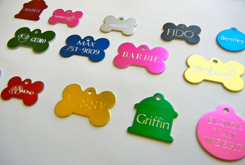 Assorted colorful bone-shaped engraved pet ID tags with visible names