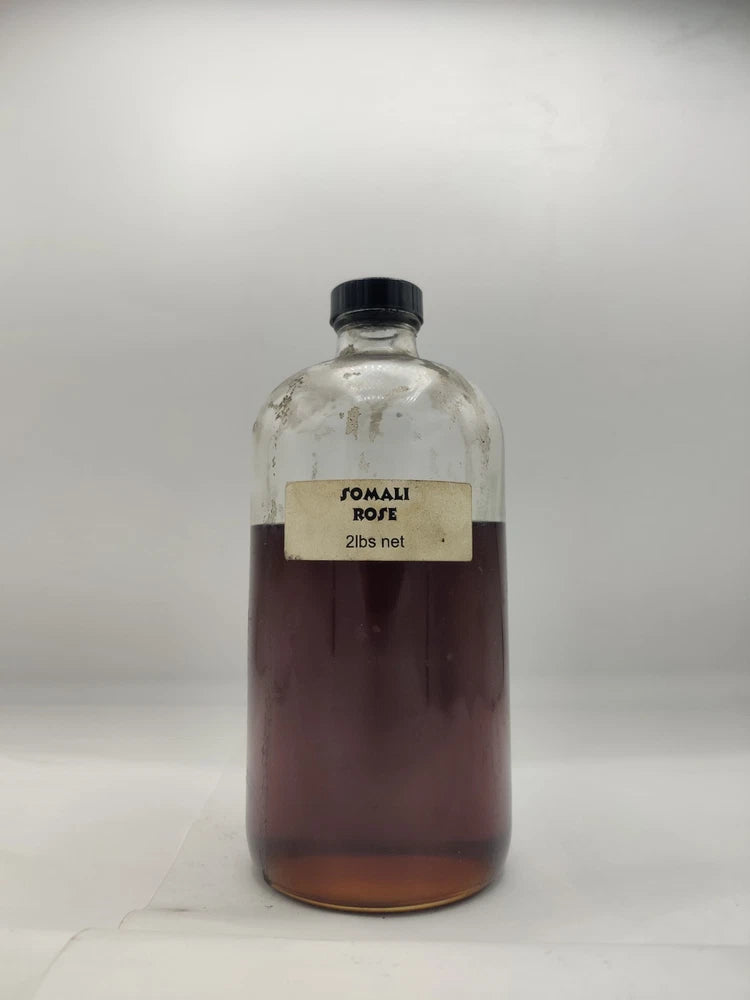 Rose fragrances oil bottle with black cap, rose-colored liquid, front label