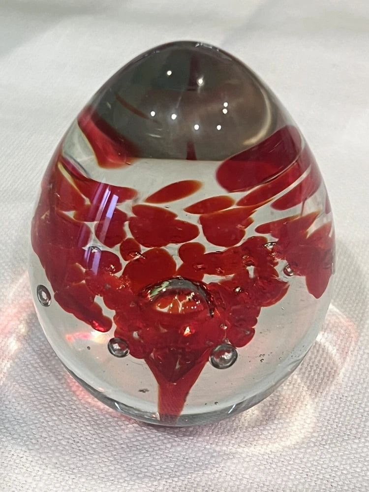 Vintage red art glass egg paperweight with floral swirl and clear base