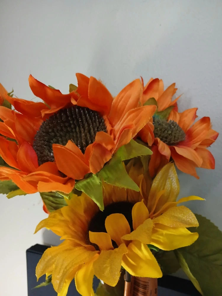 Silk faux sunflower arrangement with orange and yellow blooms and green leaves