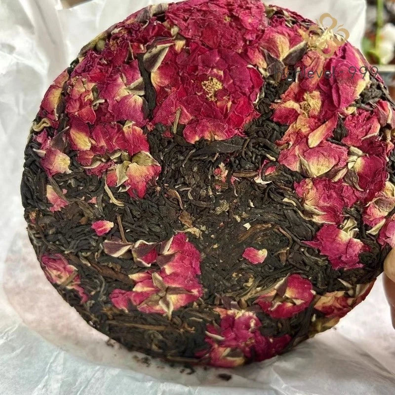 Round rose flower tea cake with dark tea leaves and dried pink petals