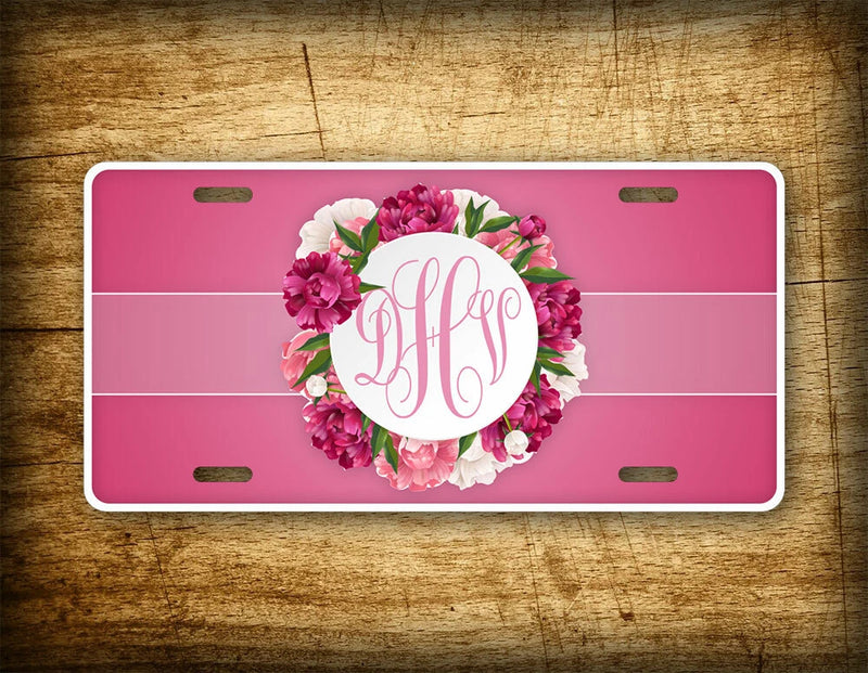 Pink license plate with white border, peony flower wreath and monogram in center