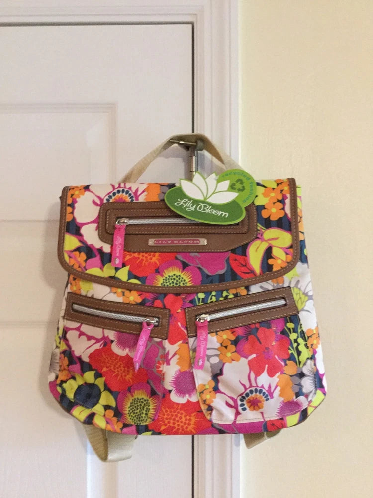 Multi-color floral backpack with front zip pockets and adjustable tan straps, green tag