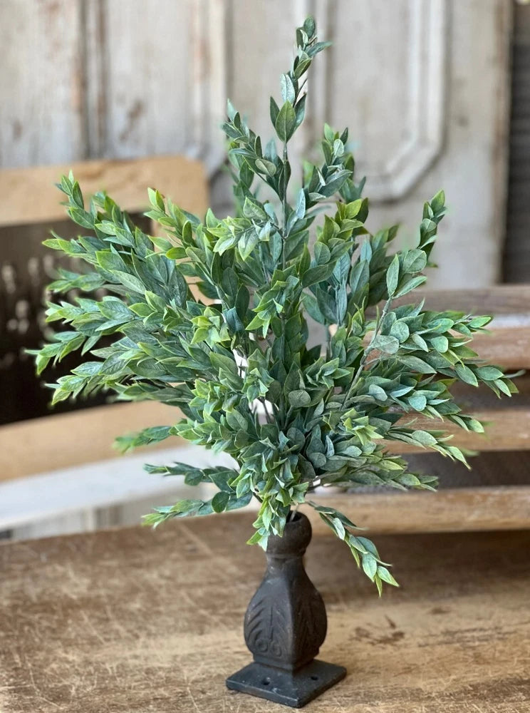 Artificial greenery leaf spray with rainwashed green leaves on dark stone vase