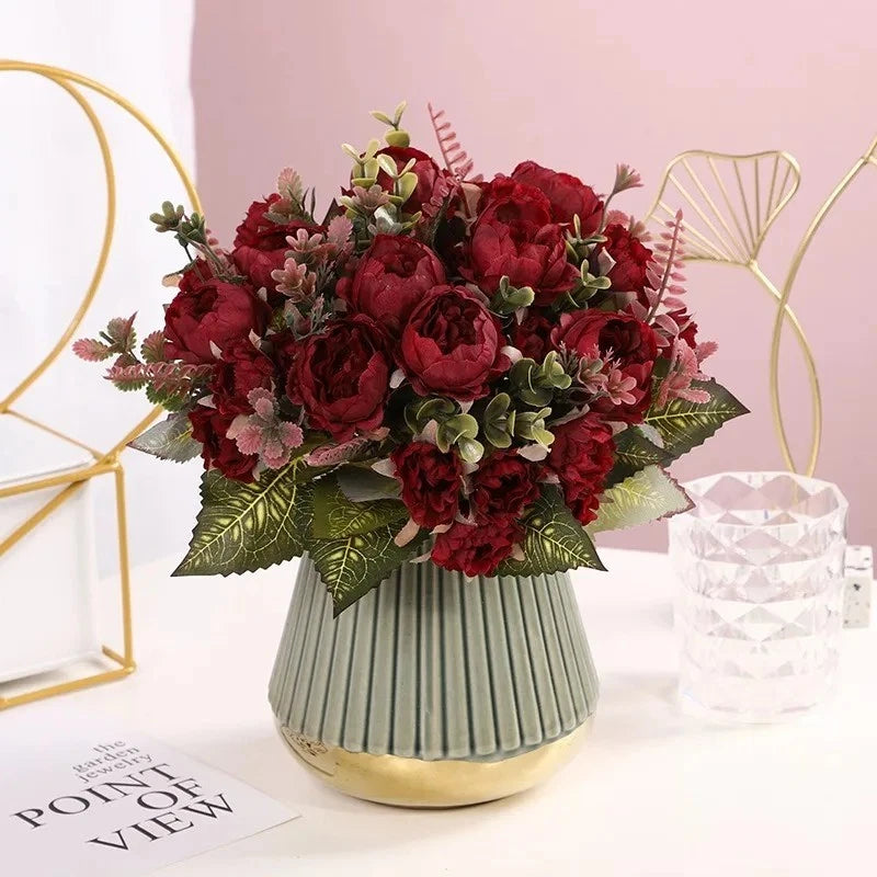 Artificial peony flower bouquet in a light green pleated vase with red blooms and leaves