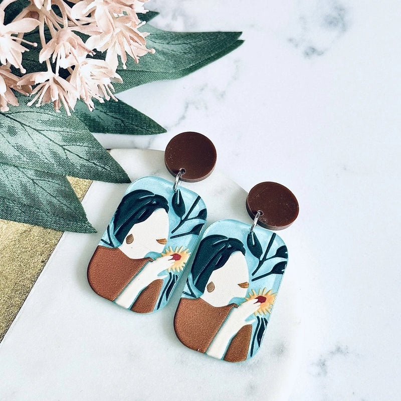 Floral teal acrylic dangle earrings with brown backs and leaf-painted arches
