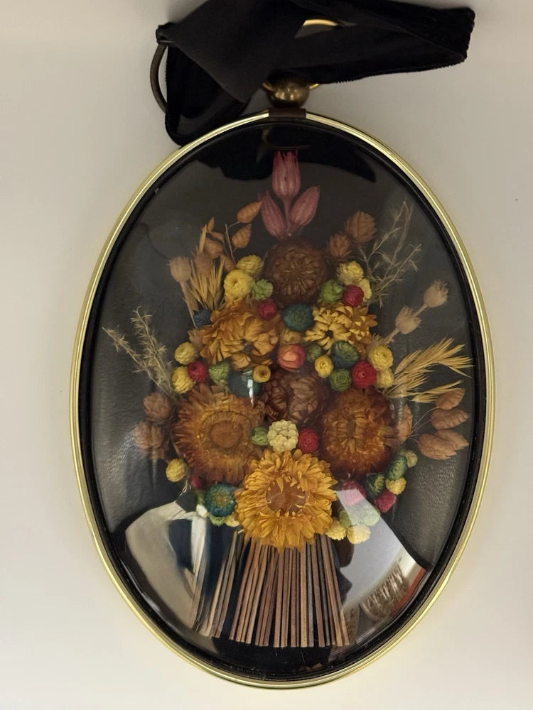 Oval dried flower bouquet wall art in gold-rim convex glass frame