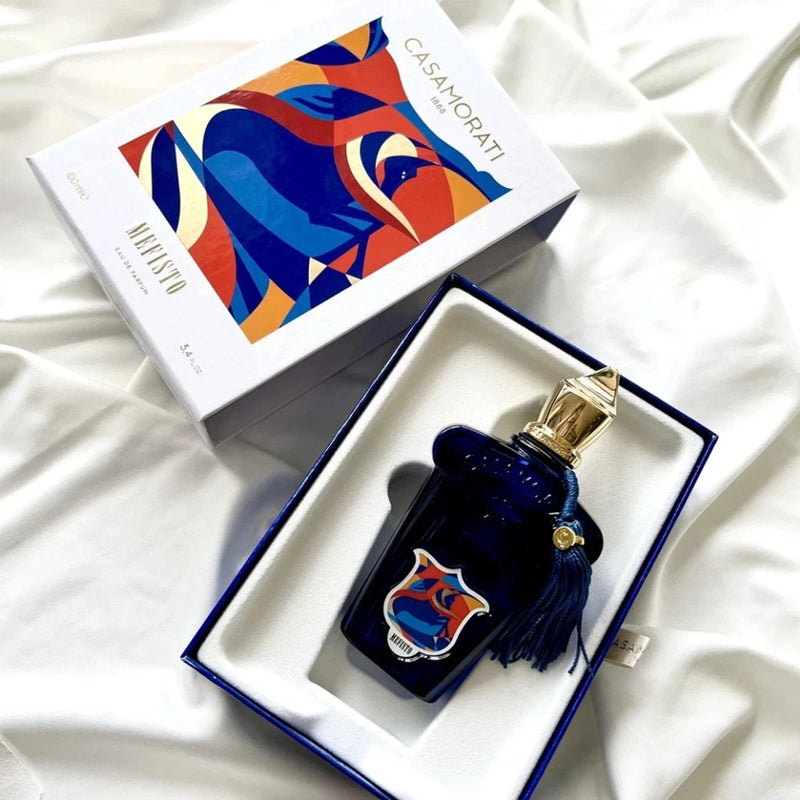 Men's eau de parfum bottle in navy box, dark blue glass with gold cap and tassel