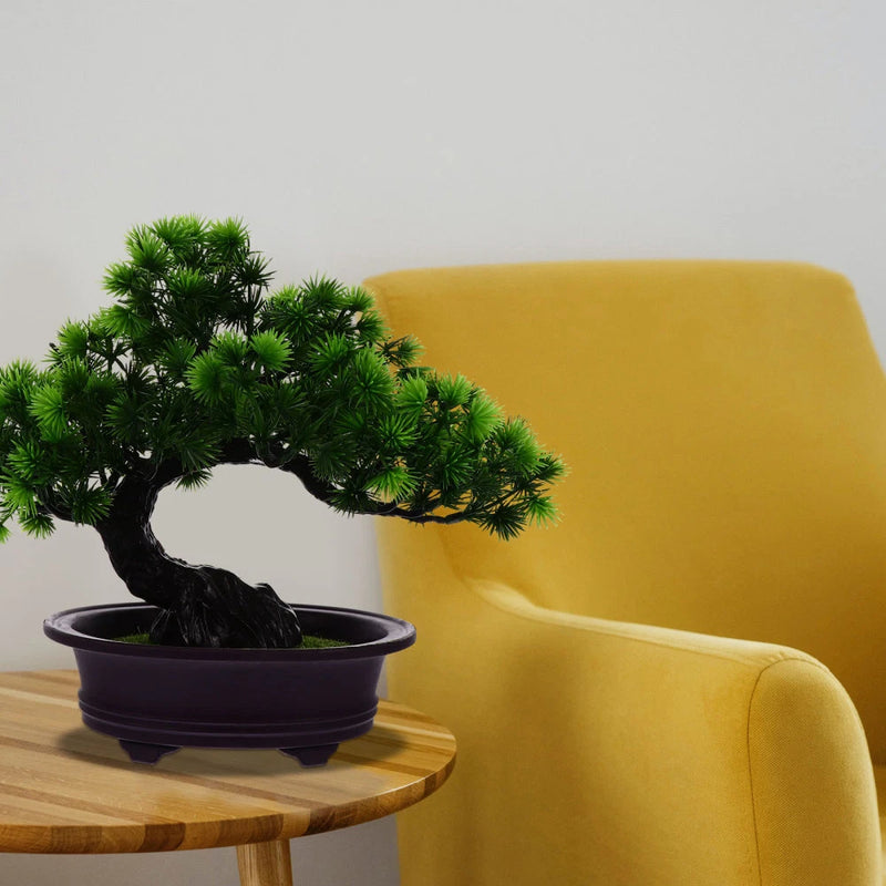 Artificial bonsai pine tree with green needles in a dark round planter pot