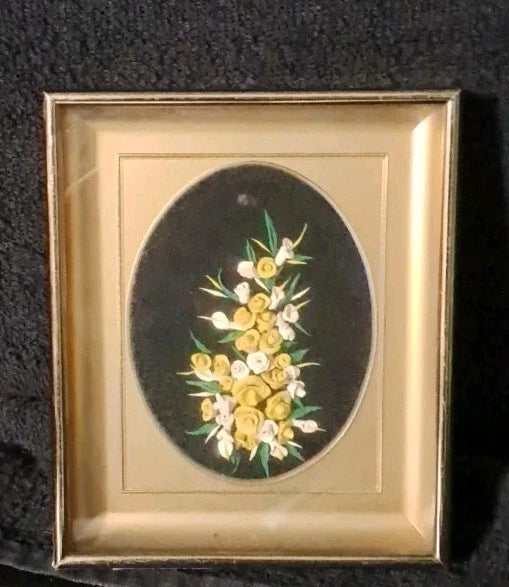 Framed dried floral art with yellow and white blooms on black oval velvet