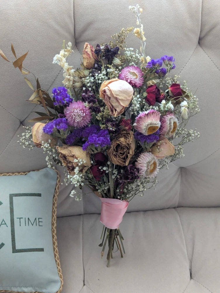 Dried mixed flower bouquet with purple statice, rose heads, and light pink blooms