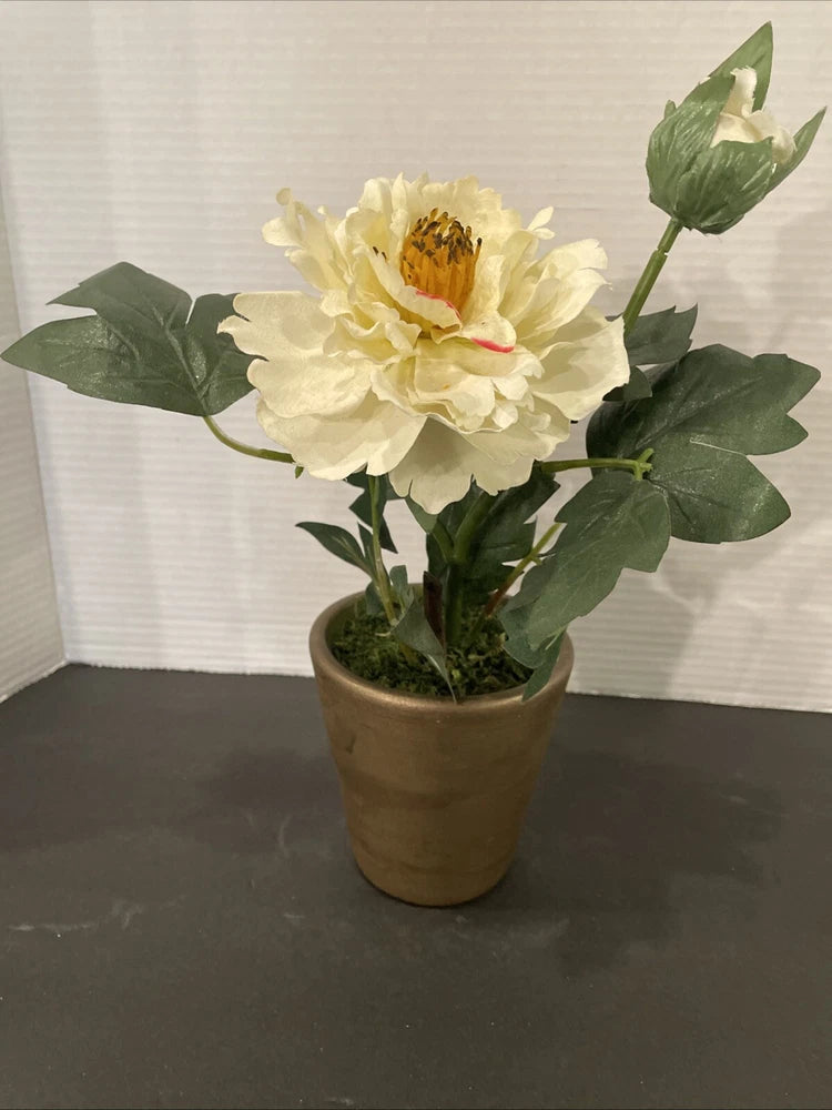 Artificial peony flower in a small terracotta pot with green leaves