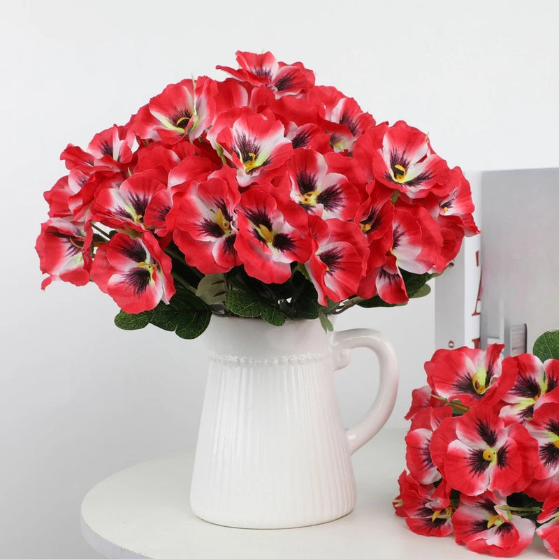Silk flower bouquet with red and pink pansy-style blooms in a white vase