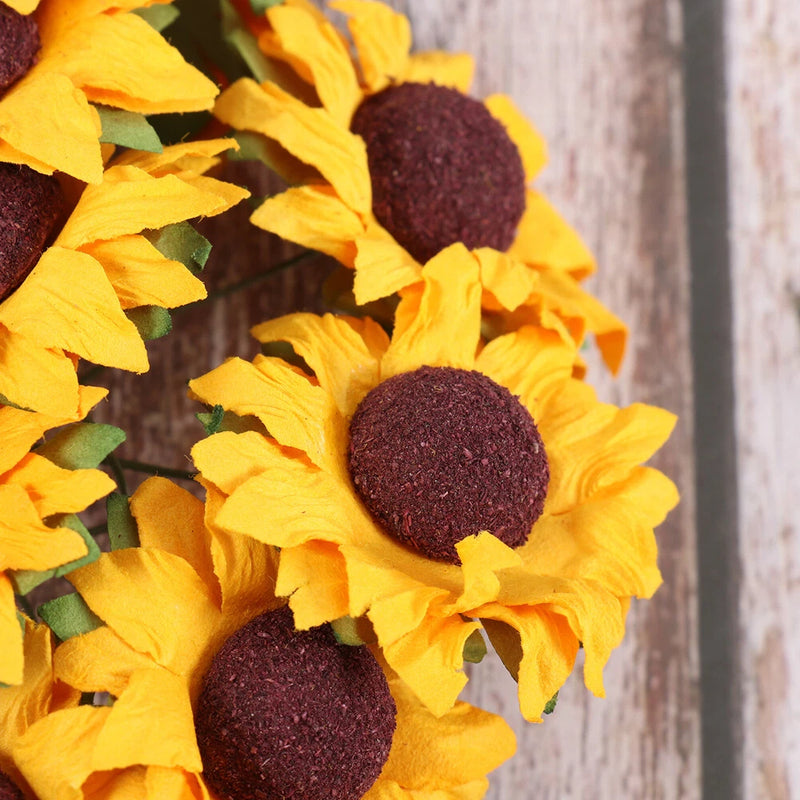 Mini artificial paper sunflowers, yellow petals with dark brown centers, close-up bunch