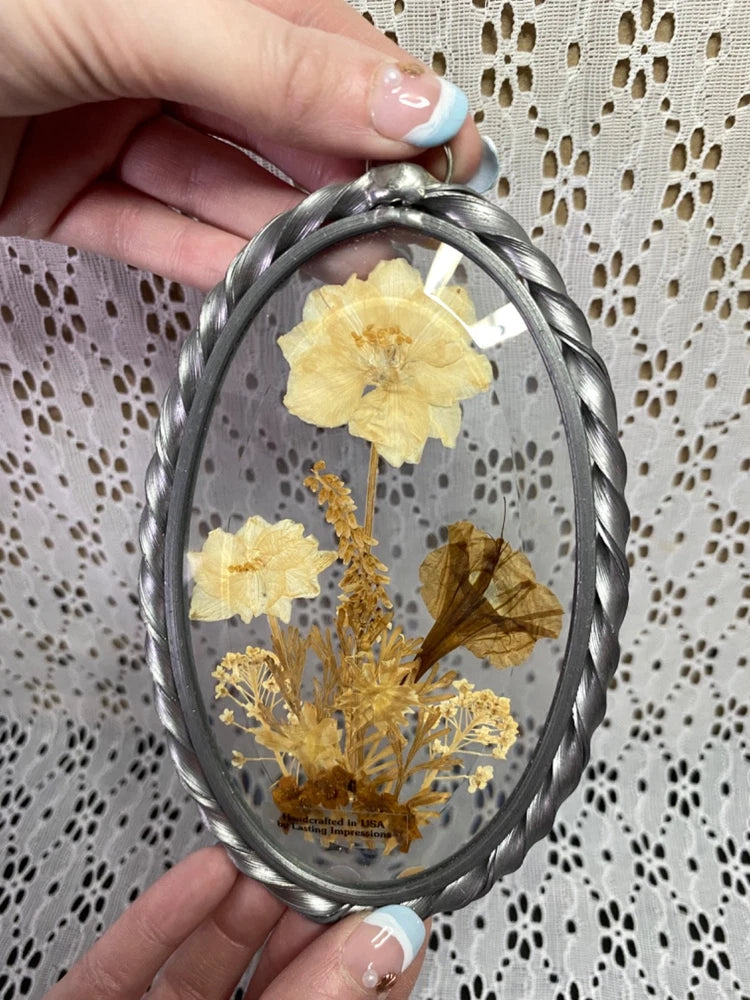 Oval pewter frame suncatcher with pressed yellow dried flowers inside