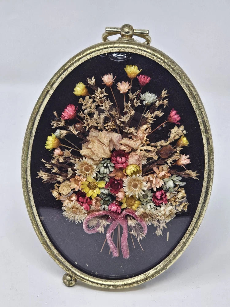 Oval gold-framed glass dried flower bouquet wall art with pink, yellow, beige blooms