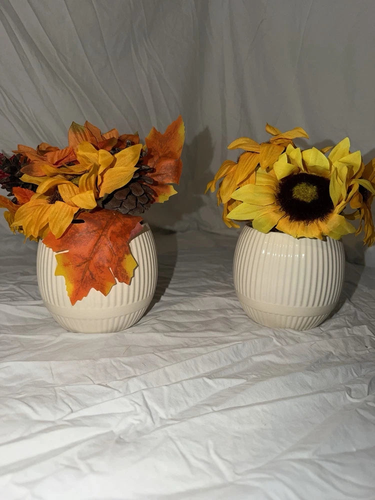 Two white ceramic vases with sunflower arrangement, yellow petals and dark centers