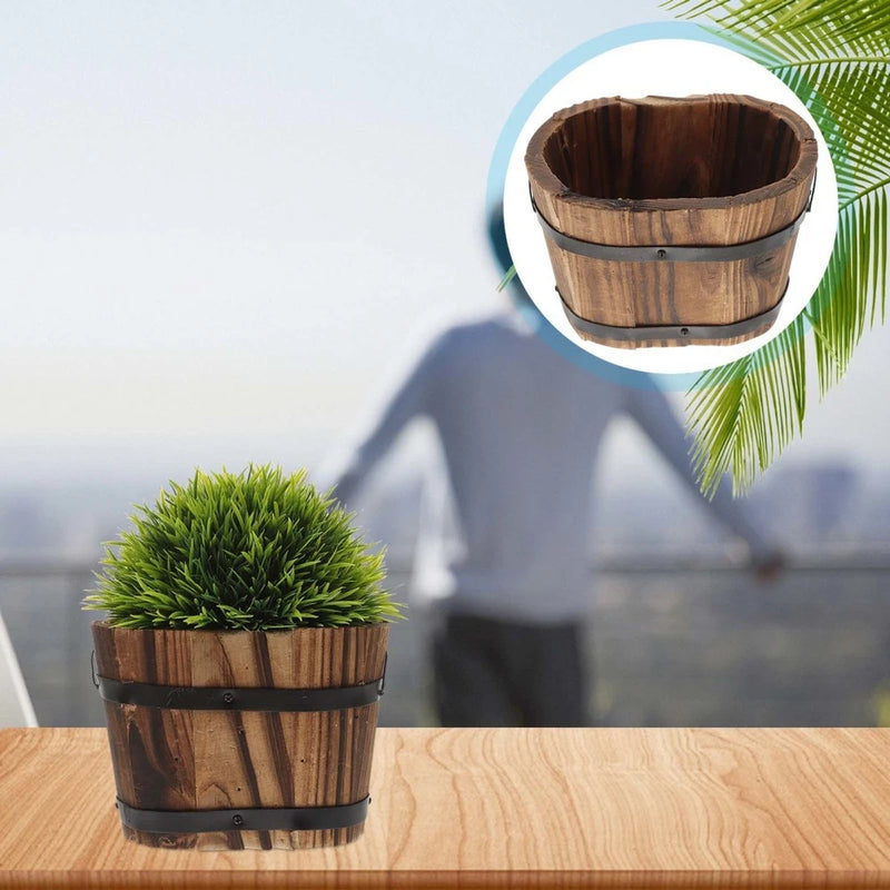 Small barrel-style wooden planter pot with dark rim, holding a green succulent