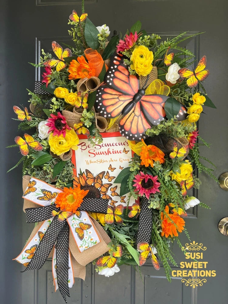 Summer butterfly floral wreath with orange, yellow, pink blooms and polka-dot ribbon bow