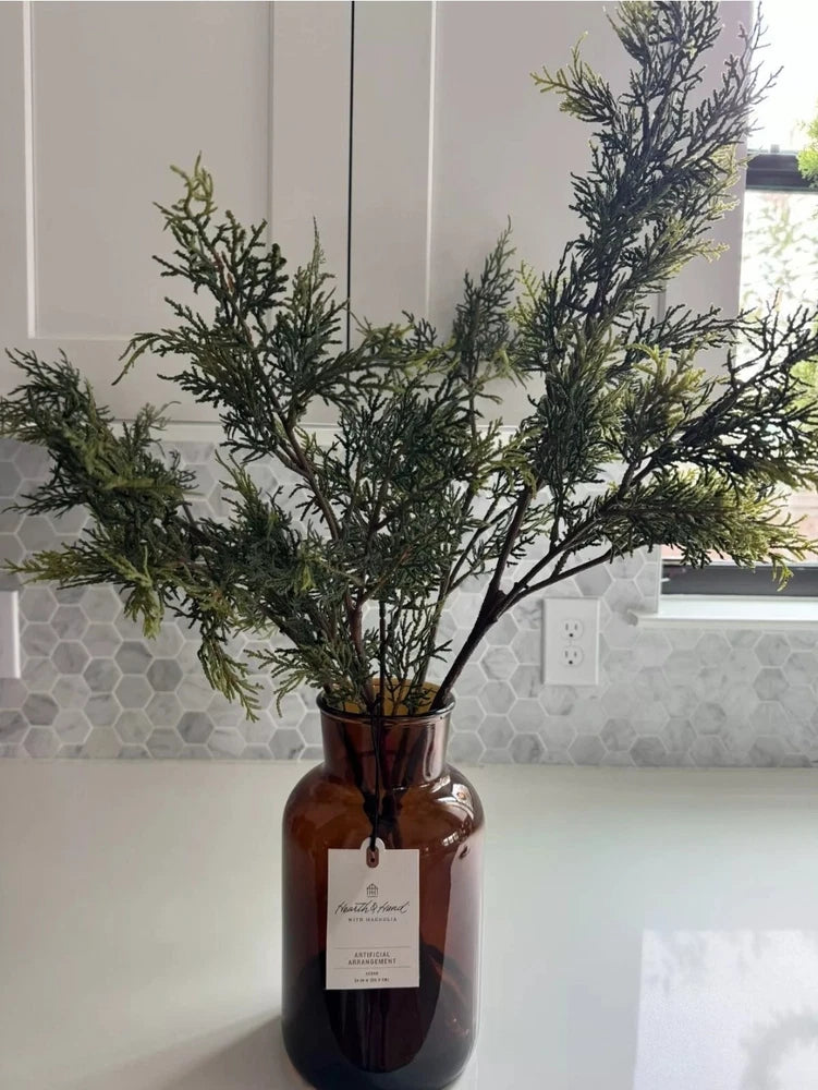 24-inch faux cedar branch Christmas arrangement in amber glass vase