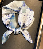 Light blue silk scarf with vintage peony print, tied in a bow knot.
