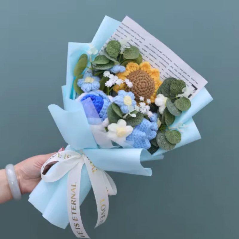 Crocheted sunflower and rose bouquet wrapped in light blue paper with ribbon