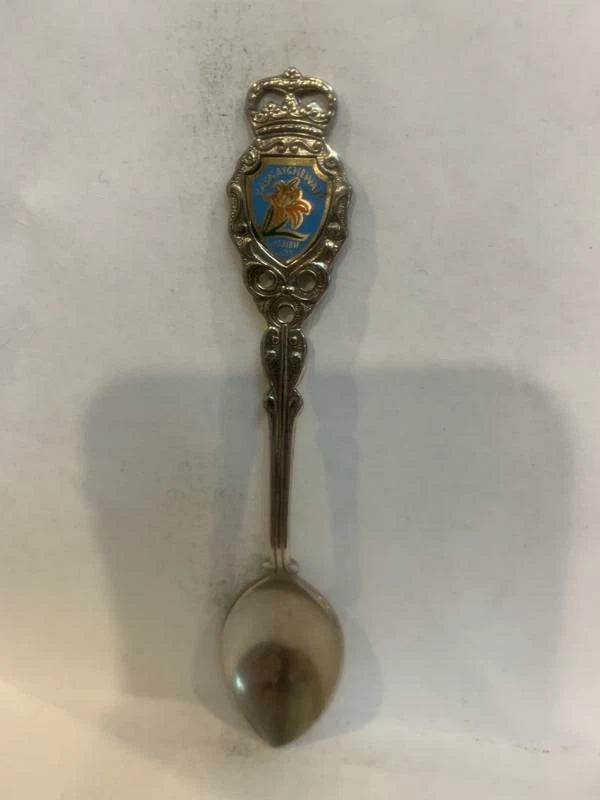 Souvenir metal spoon with ornate crest emblem on handle