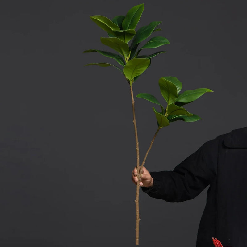 Artificial magnolia tree branch with two green leaf clusters on a tall stem
