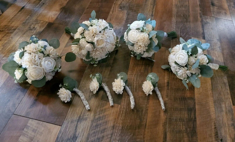 Off-white bridal bouquet set with white roses, eucalyptus leaves, and ribbon handles