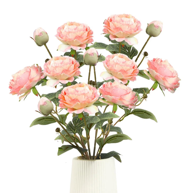 Artificial pink peony bouquet with faux silk blooms on green stems, set in white vase