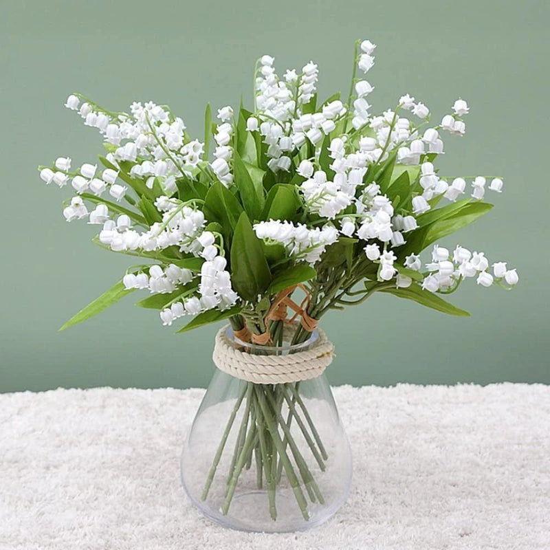Artificial lily of the valley flower bouquet with white bell blooms and green leaves in vase