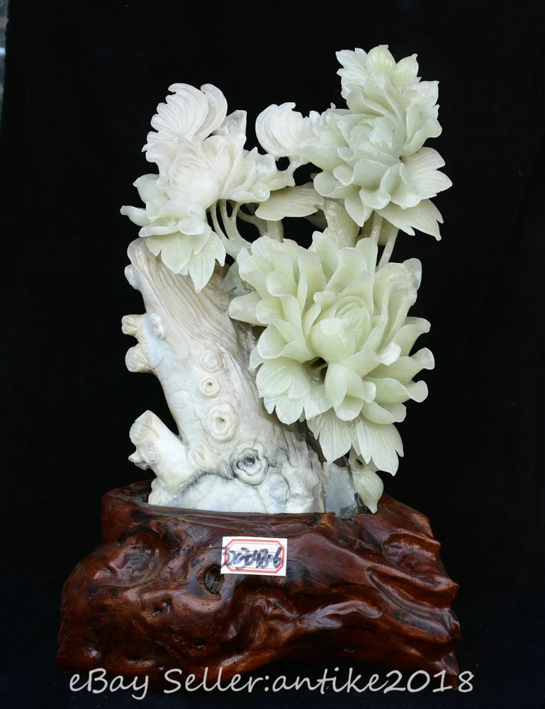 Carved jade-style peony and butterfly statue with floral bouquet on dark wood base