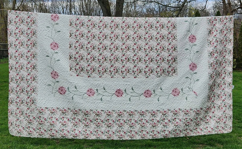 Pink carnation embroidered quilted bedspread with floral vine border, light background