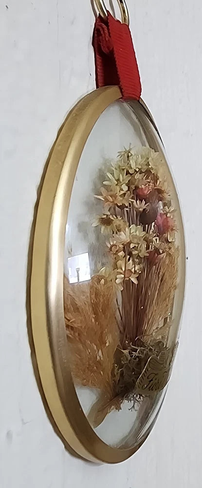 Oval glass dried flower frame with gold rim and pressed flowers, red hanging ribbon