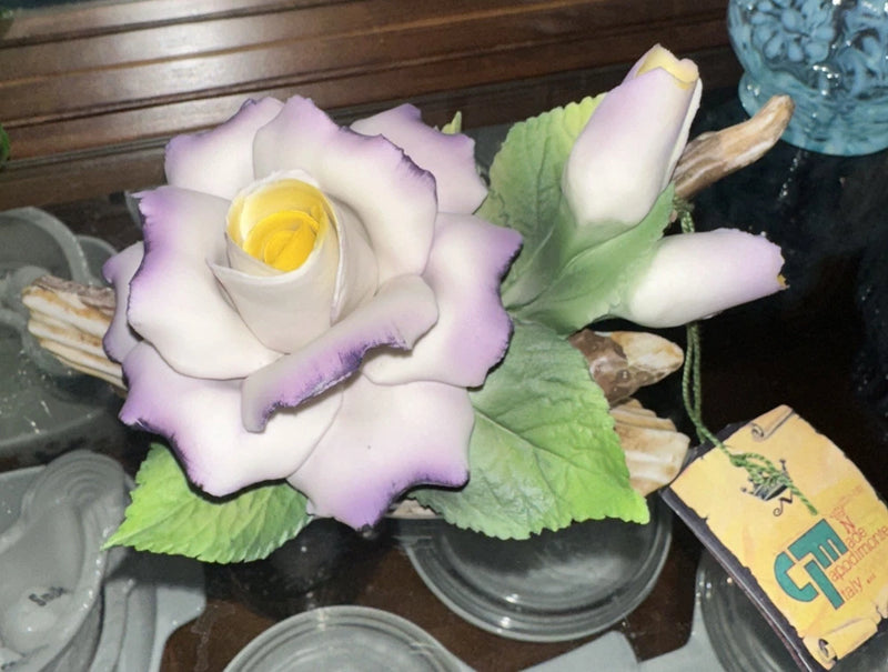 Porcelain rose bouquet with pale purple and white blossoms and green leaves