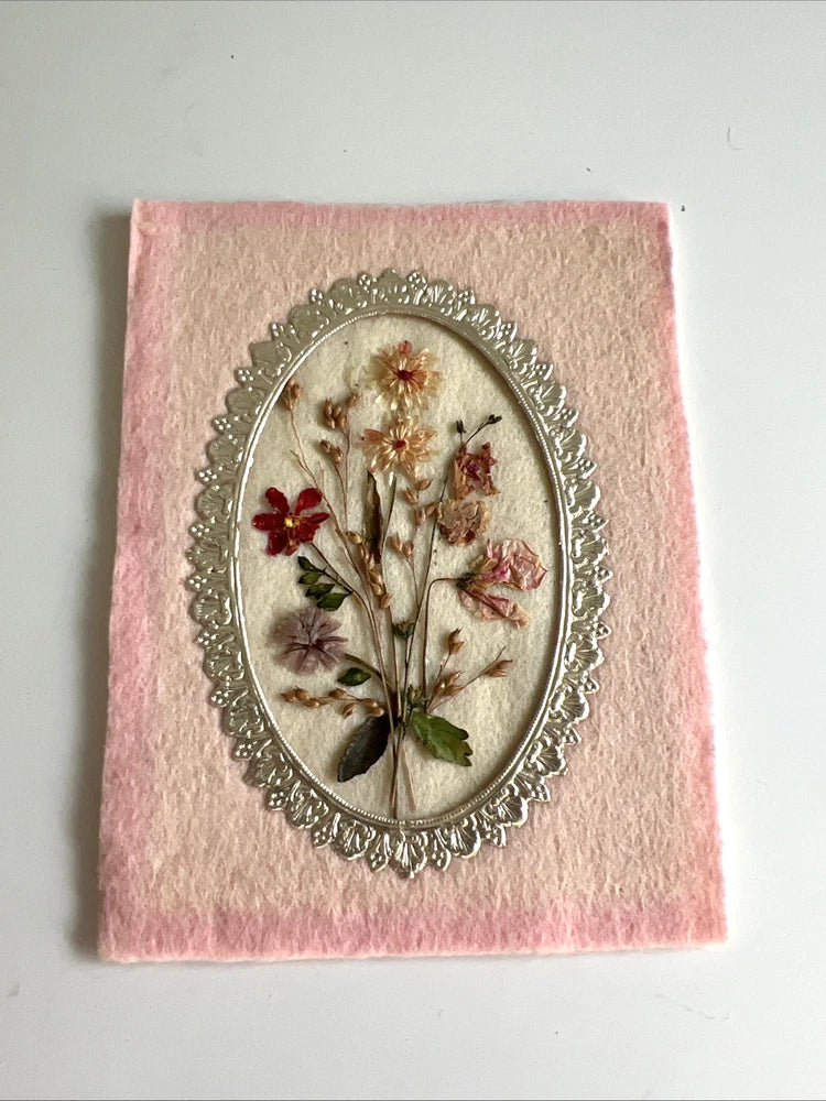 Oval pressed flower dried art, small pink/red blooms in ornate silver frame on pink backing